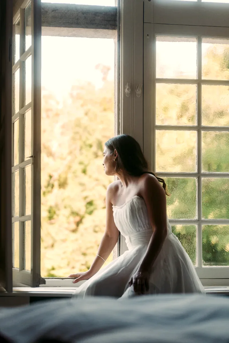 La mariée assise devant une fenêtre du château